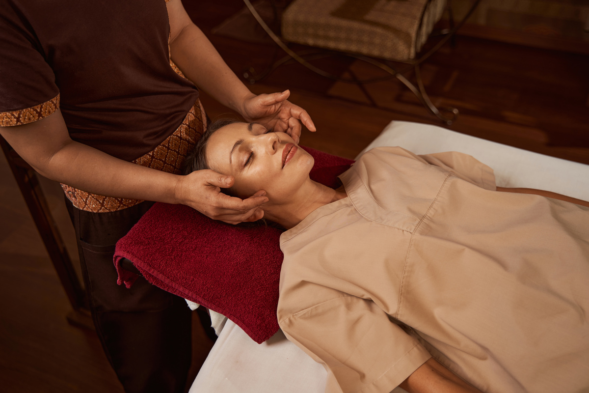 Professional masseuse massaging acupressure points on client face